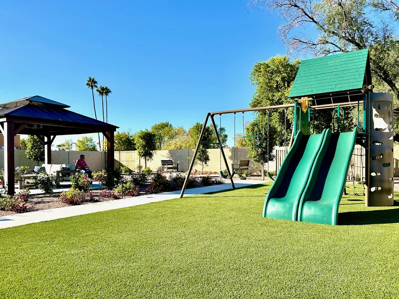 Lawn, swings and gazebo under blue sky