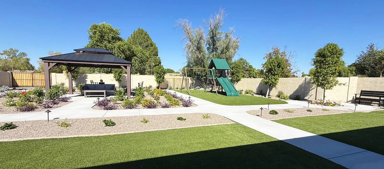Wide view of the landscaped backyard with lawn, gazebo and paths