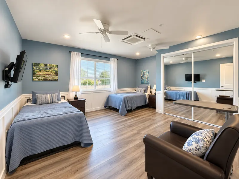 Renovated companionship room with two beds, TVs and framed art