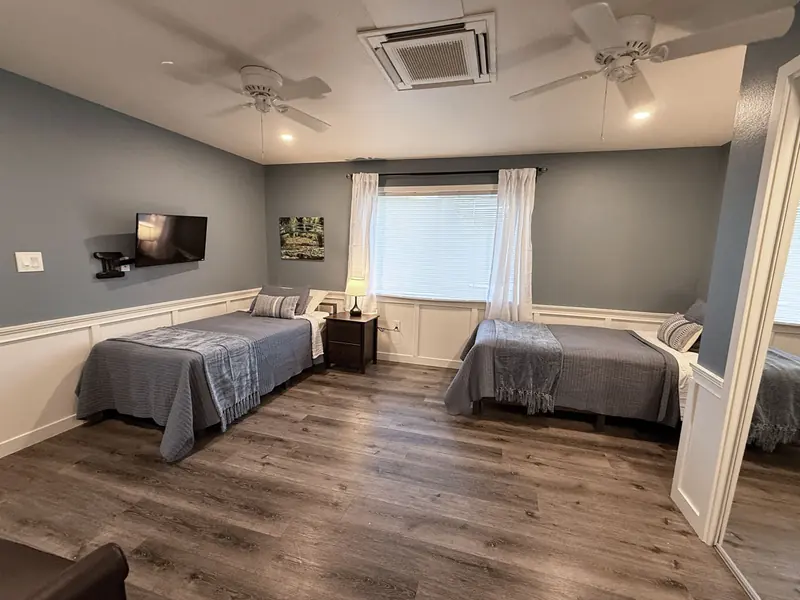 Room with two beds, ceiling fan and wall-mounted TV