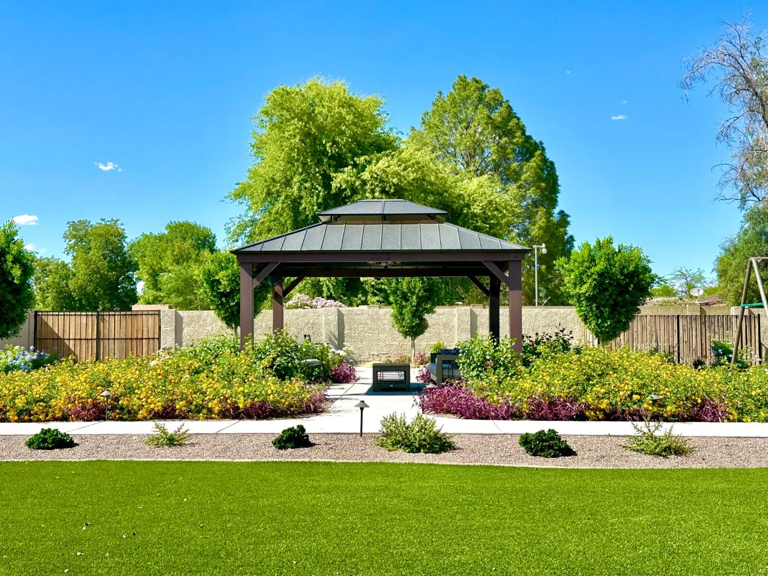 Gazebo surrounded by flower beds and lawn in the backyard